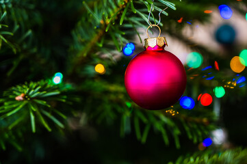 A closeup shot of a pink Christmas ball on a Christmas tree decorated with led lights