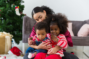 Happy African American family on Christmas day. Mother, little daughter and little son enjoying Christmas holiday
