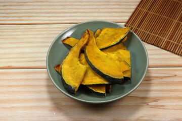Roasted sliced fresh pumpkin on the plate. Famous vegetarian snack for diet. High fiber and nutrition food. 