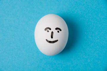 Fototapeta na wymiar An egg with a smiling face. Isolate on a blue background. Concept of joy, happiness and good mood