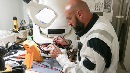 Engineer man measuring electronic product on test bench in his lab.