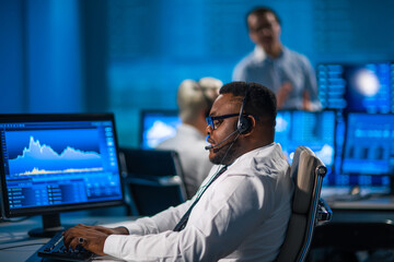 Team of brokers is working in office using workstation and analysis technology. Workplace of professional traders. Global financial markets, business, currency exchange and banking concepts.