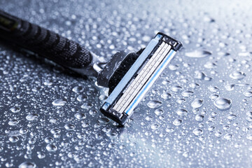 Razor close-up with water drops on a gray background.