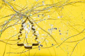 silver Christmas themed cookie cutter on a bright yellow background