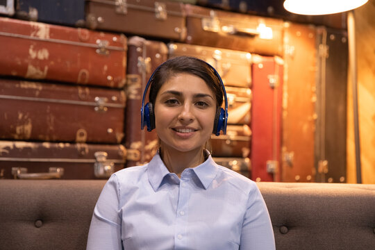 Close up headshot portrait of young Indian woman in headphones talk on video call with client or customer. Millennial ethnic female employee have webcam digital virtual conference or online meeting.