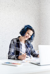 Designer working with colour palettes and laptop in her studio