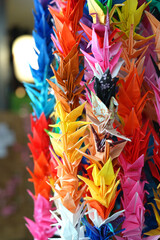 Origami multicolor paper birds decoration in a Japanese garden in nature, wedding origami cranes