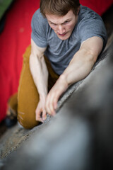 A rock climber climbing on a boulder rock outdoors. Group of friends involved in sports outside.