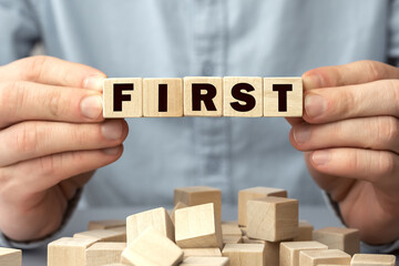 The word FIRST made from wooden cubes. Shallow depth of field on the cubes