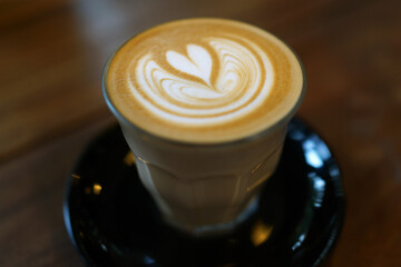 Coffee to go. Fresh latte in a cup on a wooden table in a cafe.