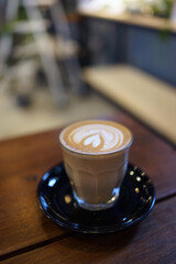 Coffee to go. Fresh latte in a cup on a wooden table in a cafe.