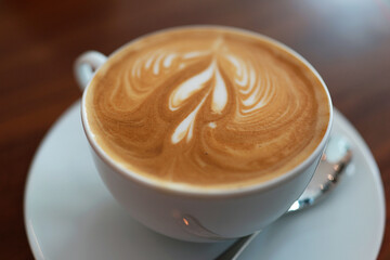 Coffee to go. Fresh latte in a cup on a wooden table in a cafe.