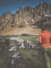 Young woman in a scenic alpine setting walking towards her car (color toned image)