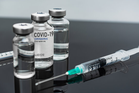 Covid19 Vaccine syringes and medicine bottles in reflecting dark table