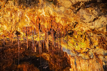 Selectively focused hair thin stalactites with water droplets in the colorful Fairy Grottoes in Saalfeld