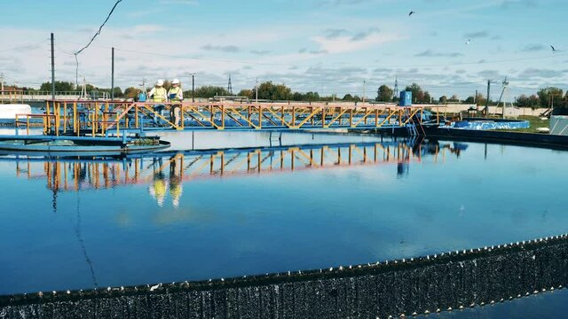 Wastewater operators inspecting a circular clarifier in daylight