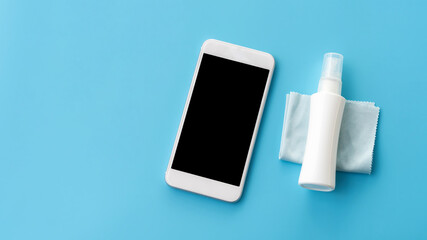 White smartphone and alcohol spray on a blue background.