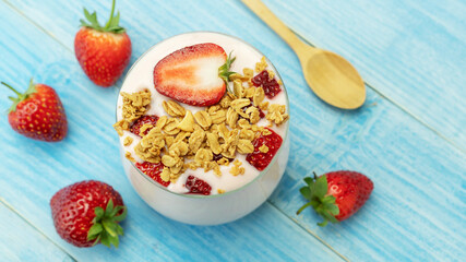 Strawberry yogurt on a blue wooden table.