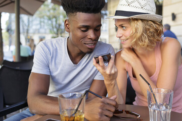 young cheerful couple making phone call in cafe bar
