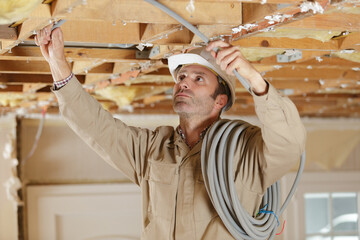 contractor passing cabling through roof timbers