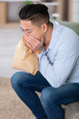stressed asian man breathing with paper bag