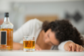 bottle and glass of alcohol with woman on background