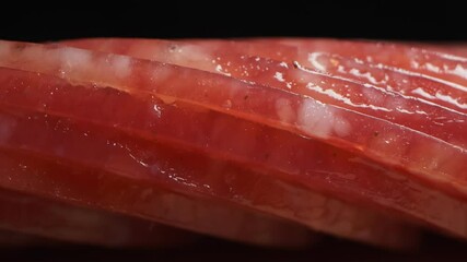 extreme close-up, detailed. salami sausage cut into thin pieces on a wooden board, changing lighting from dark to light