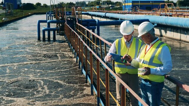 Wastewater operators checking water condition at a sewage treatment plant