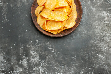 Half shot of delicious homemade potato chips on a brown plate on gray table