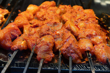 Cooking raw pork skewers marinated in spices on a skewer