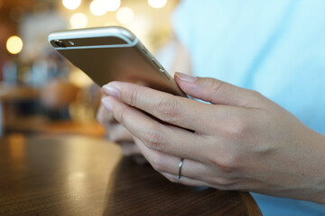 Woman sitting and using smartphone in a cafe.