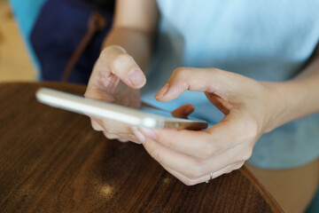 Woman sitting and using smartphone in a cafe.