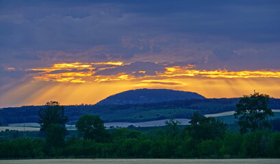 Obraz premium Hill under clouds illuminated by sun