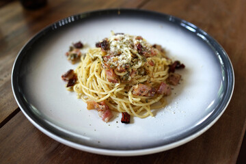 Spaghetti with dried chili and bacon on a plate close up.