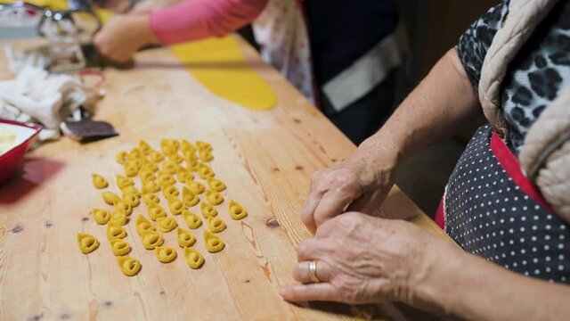 Crop women cooking traditional tortellini in kitchen