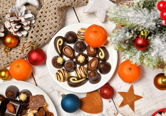 sweet food top view background for merry christmas or new year holiday decoration - chocolate candies, tangerines, cookies on white wood