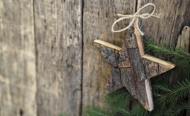 Rustic wooden greeting background with a star hanging from a natural rope. Christmas or New Year background for greetings.