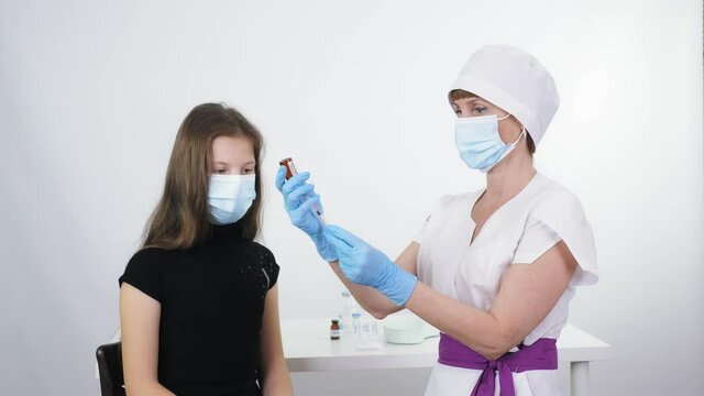 Coronavirus vaccination of children. nurse or doctor, in protective mask and medical gloves, draws liquid vaccine from small glass bottle into syringe for covid-19 vaccination. global, mass
