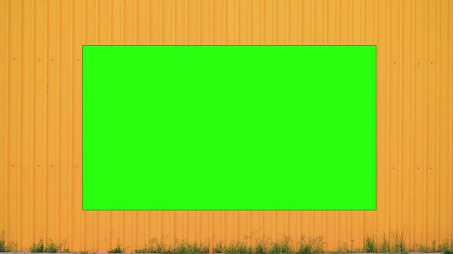 Big blank advertise green banner with chromakey hangs on yellow metal wall of city mall building