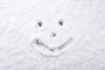 a face with a smile drawn on white snow in winter with a close-up