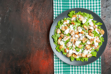 top view caesar salad on oval plate green white checkered tablecloth on dark red background free space