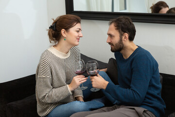 Young and happy couple drinking wine and relaxing at home
