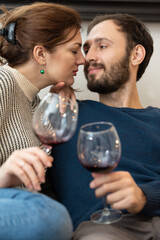 Young and happy couple drinking wine and relaxing at home