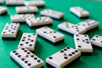 Top view of domino pieces, with selective focus, on green baize, horizontal