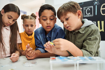 Waist up portrait of the smart children examining the test glass