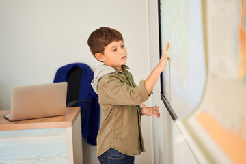 Nice caucasian boy showing at something at the interactive whiteboard