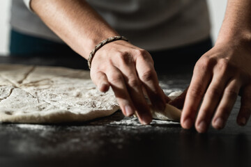 Young baker preparing dough for pizza at home - Homemade food concept