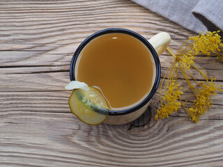 Natural fermented brine drink in a mug with cucumber on a wooden table, top view. Healthy food from vegetables with vitamins for proper nutrition