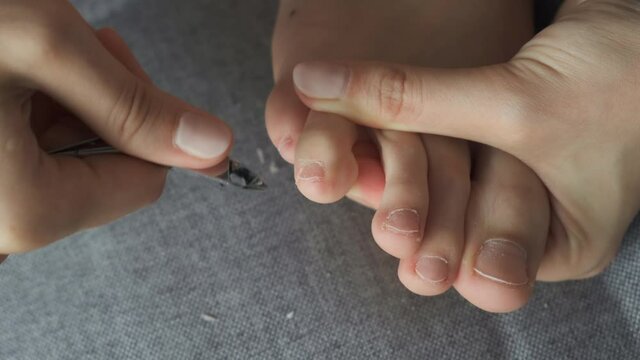 Woman is cutting cuticle on toes nails using tongs making pedicure at home, closeup view. Hygiene and care for feet.