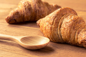 croissant on wooden table and wood spoon with filter effect